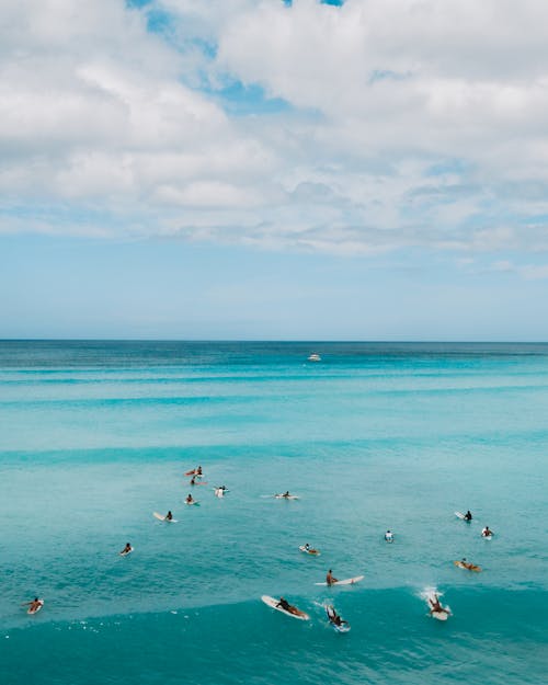 Aerial Photography of People Surfboarding on Sea Waves under the Cloudy Sky