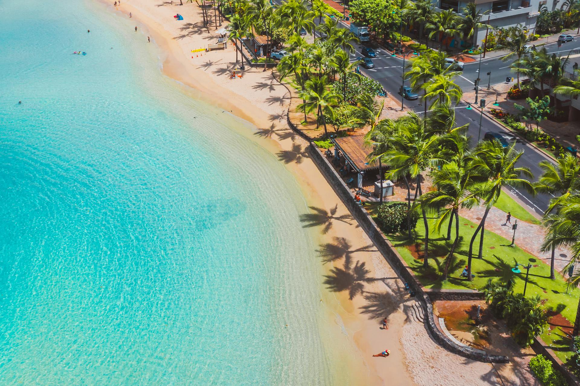 Stunning aerial photo of a tropical beach with azure water and palm trees lining the shore.