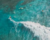 令人惊叹的航拍照片显示冲浪者在清澈的碧绿海水中冲浪