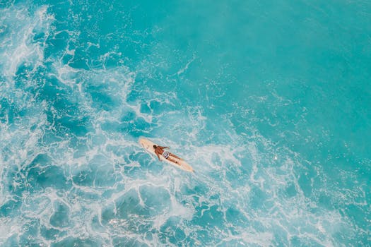 Aerial shot of a paddleboarder on the vibrant turquoise sea, capturing the essence of ocean relaxation.