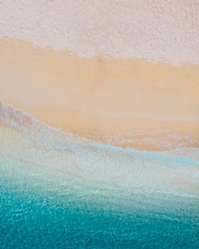 从空中俯瞰，宁静的海滩上，海浪轻柔，沙质细腻