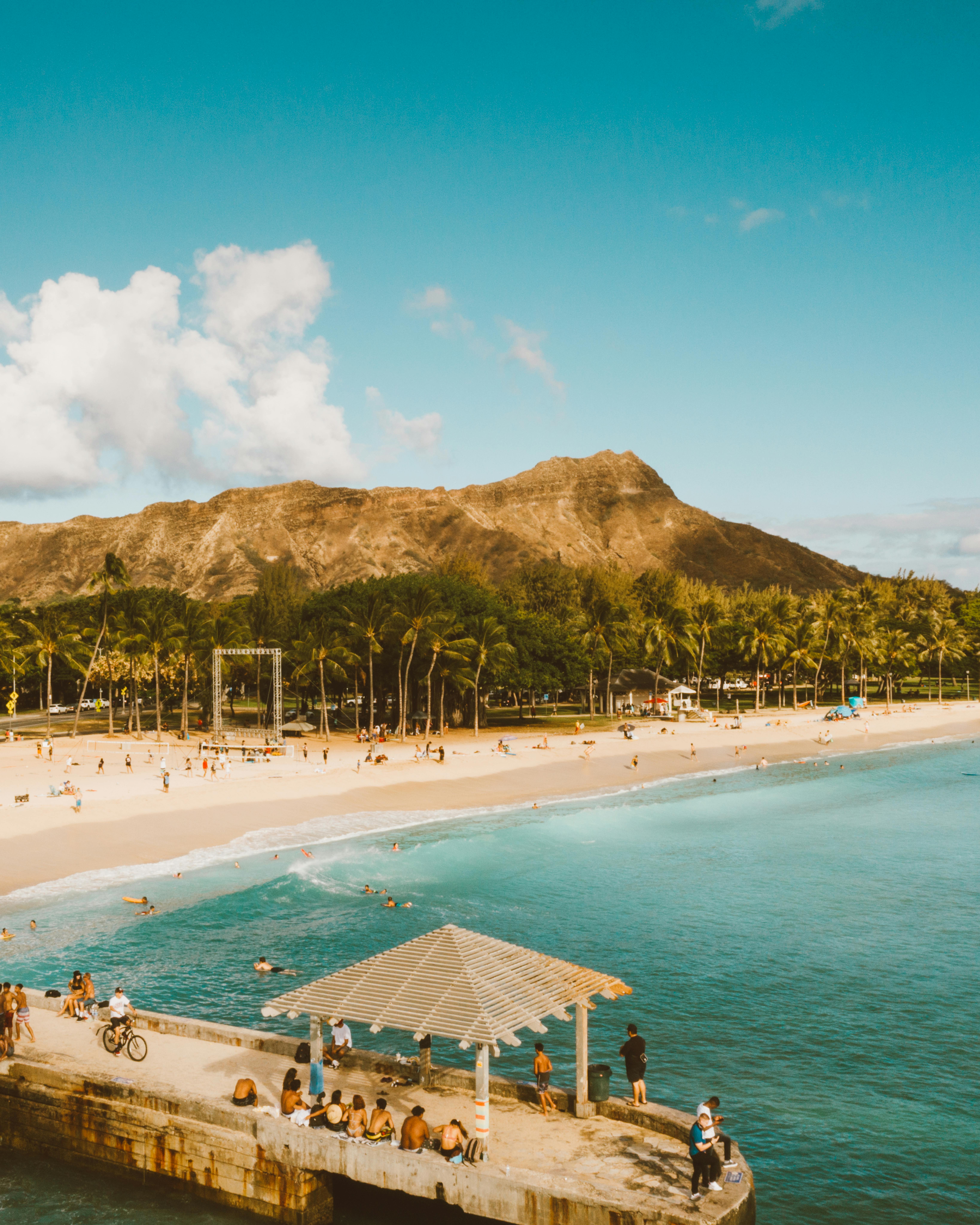 A scenic view of Diamond Head with a sunny beach and clear blue waters in Hawaii.