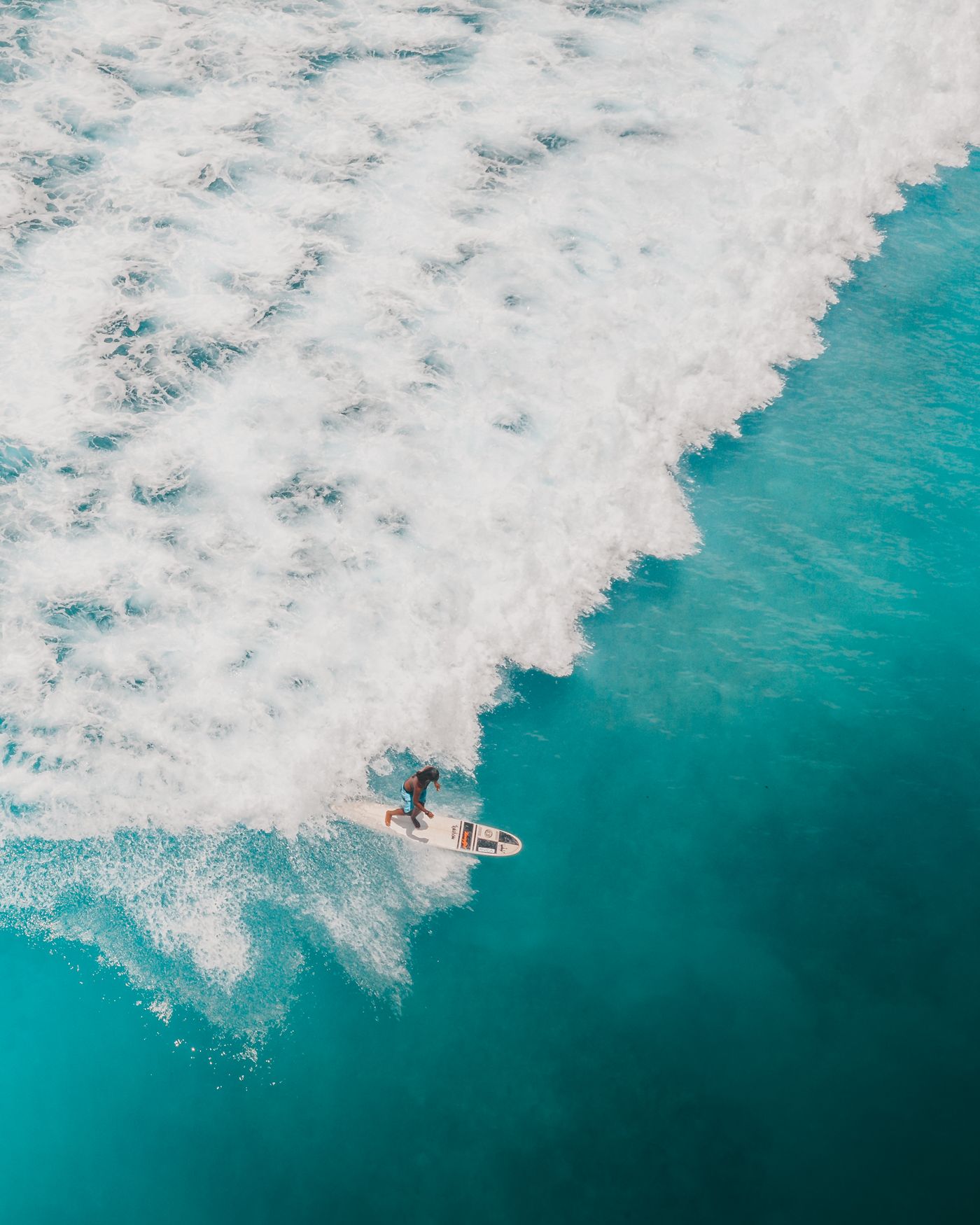 Aerial view of a surfer moving through breaking ocean waves