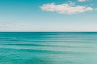 宁静的海景，游泳者在晴朗的蓝天下享受碧绿的海水，完美的夏季休闲场景