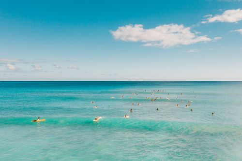 Free A vibrant seascape with people surfing under a bright sky. Stock Photo