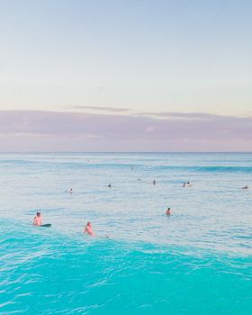 在晴朗的夏日天空下，人们在宁静的海景中游泳和冲浪