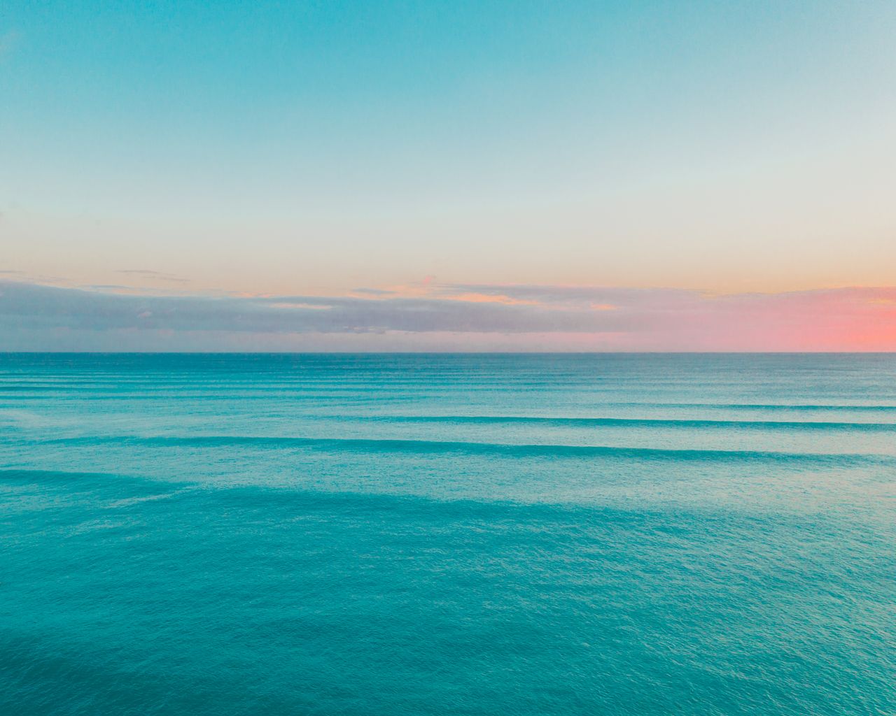 a tranquil ocean scene at sunset featuring calm waves and a colorful s
