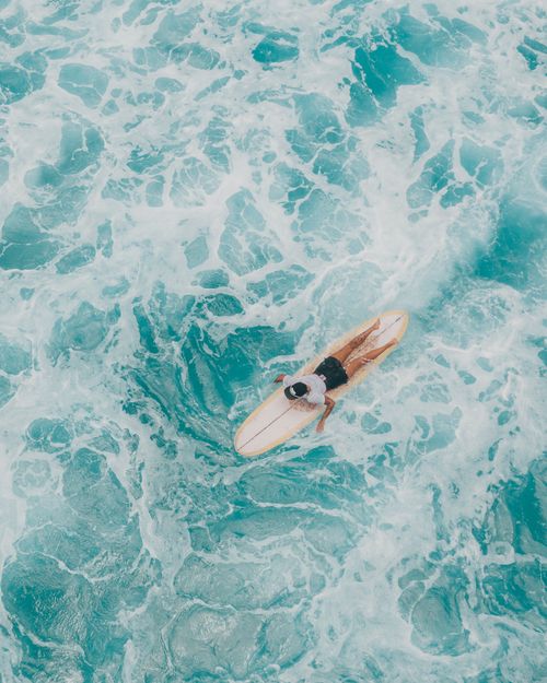 Aerial view of a surfer on turquoise water — photo by Jess Loiterton on Pexels