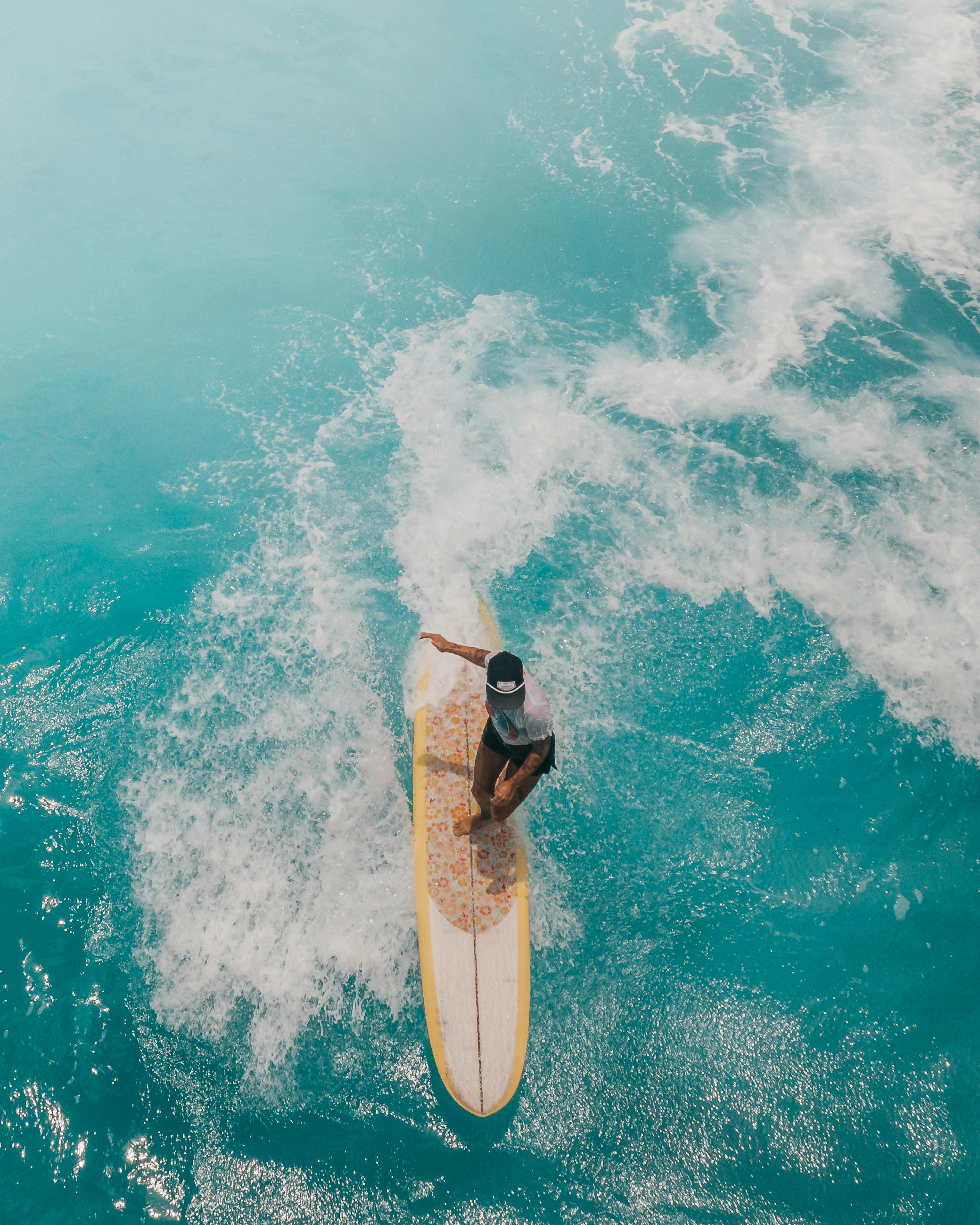 空中拍摄的照片显示，一名女子在夏日明媚的阳光下熟练地在碧绿的海浪上冲浪