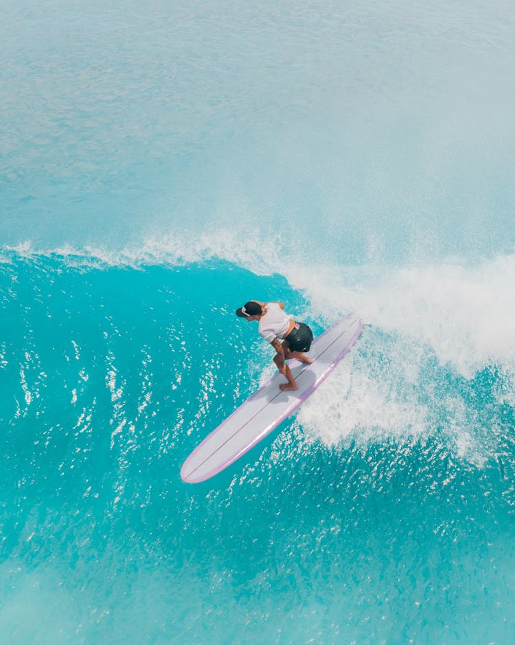 Woman Surfing On Purple Surfboard On Ocean Wave