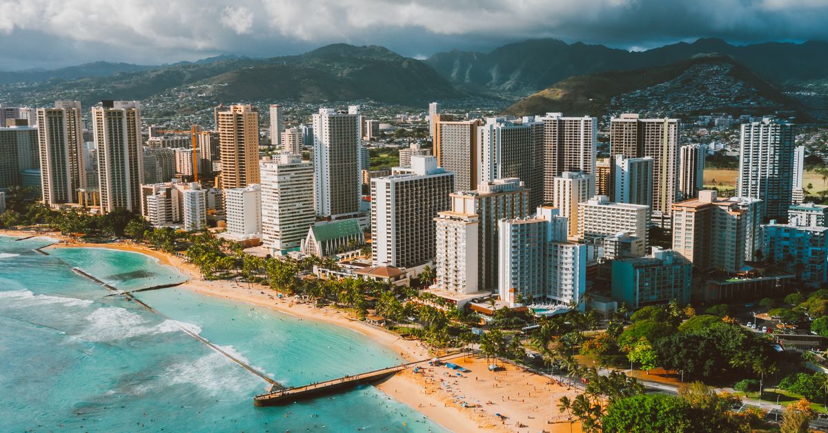 Photo by Jess Loiterton Stunning aerial view of Waikiki Beach with the Honolulu skyline and surrounding mountains.