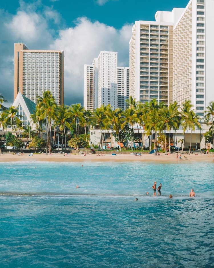 People Swimming In Sea By Luxury Resort