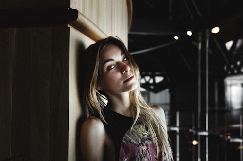 Dreamy young blondie leaning on wall and relaxing