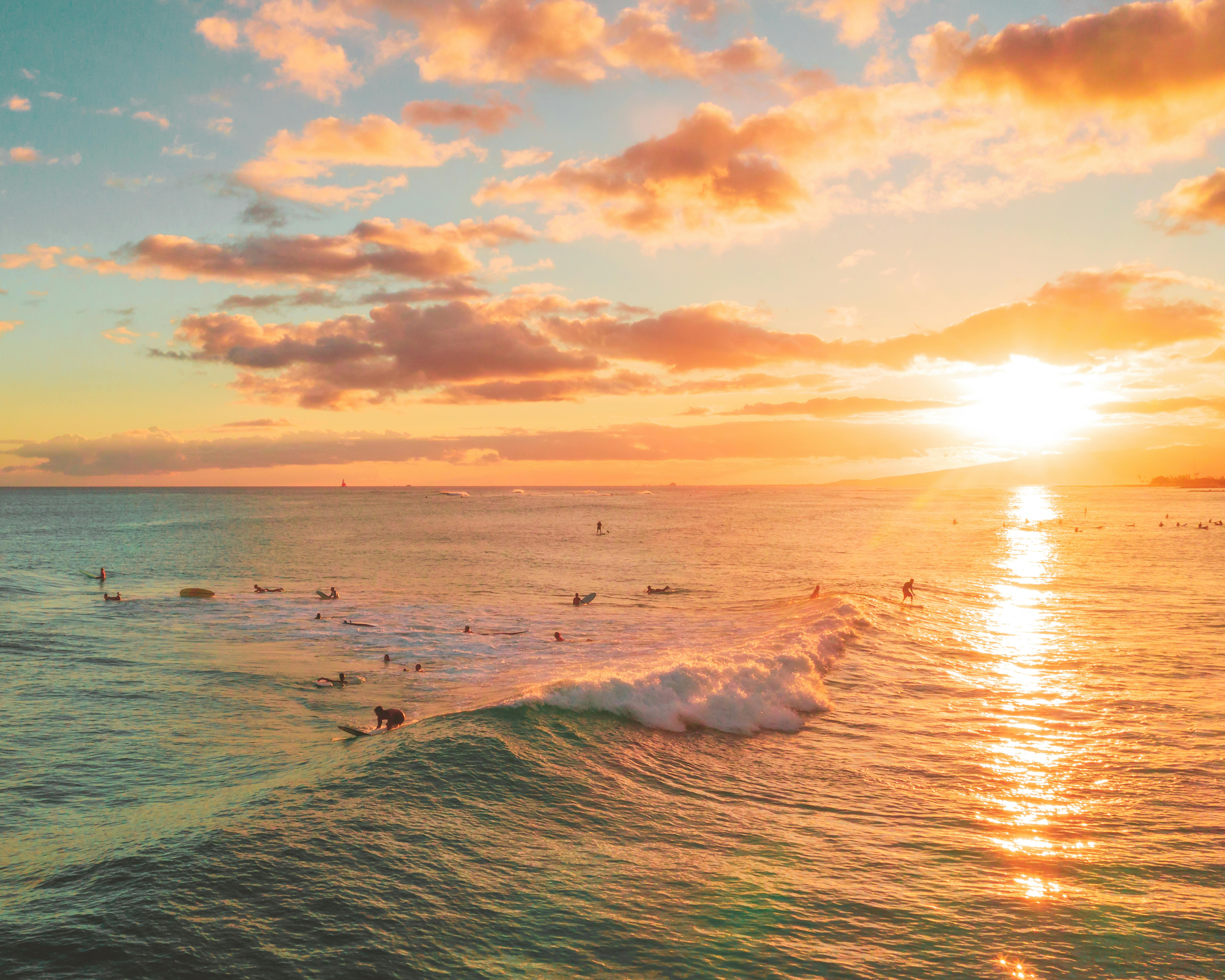 冲浪者在令人惊叹的日落天空下享受充满活力的海浪