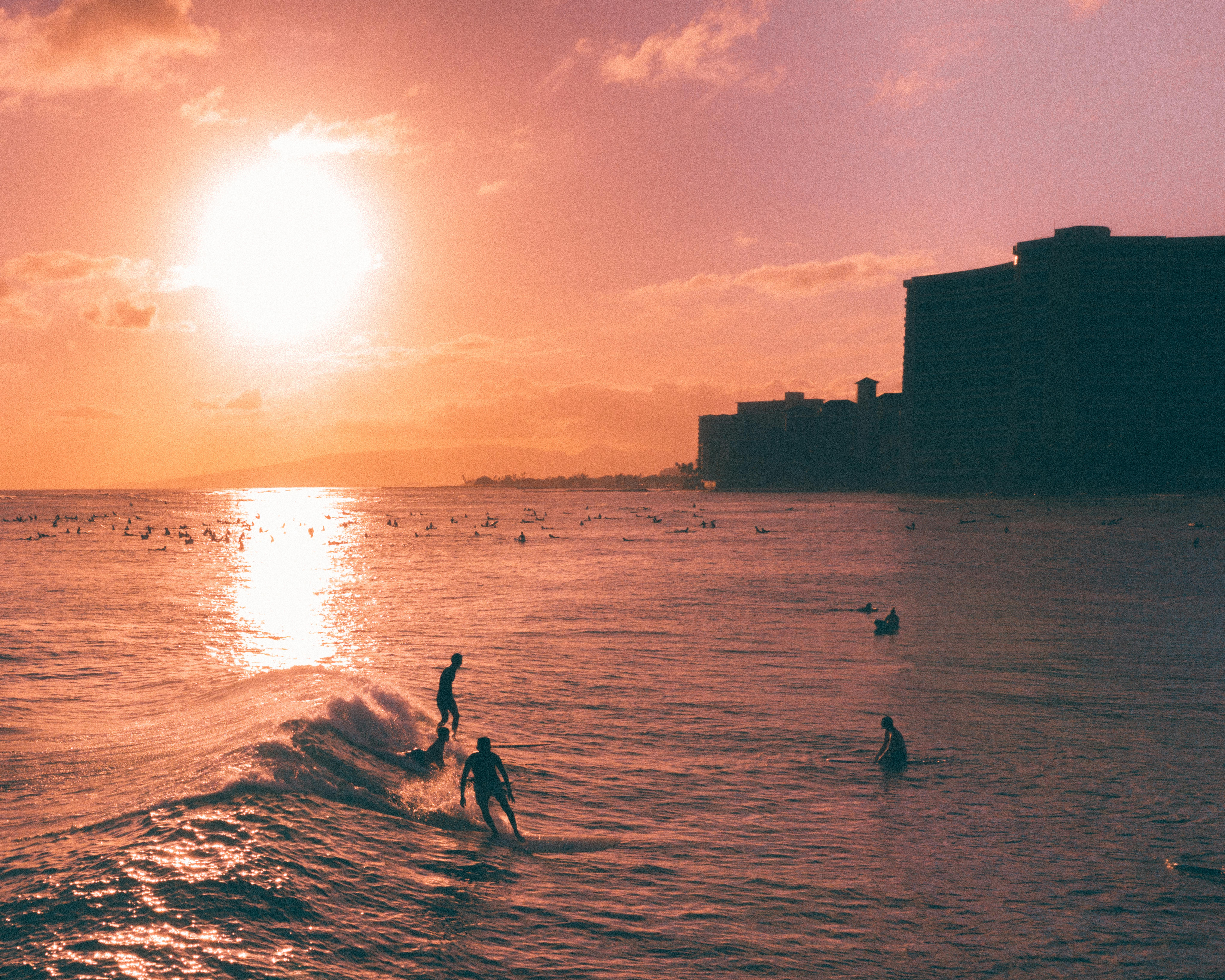 冲浪者在鲜艳的热带日落中捕捉海浪，身影映在天空的轮廓里