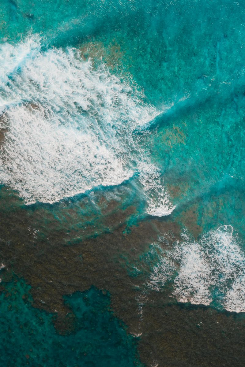 A mesmerizing aerial shot showcasing turquoise ocean waves and ripples.