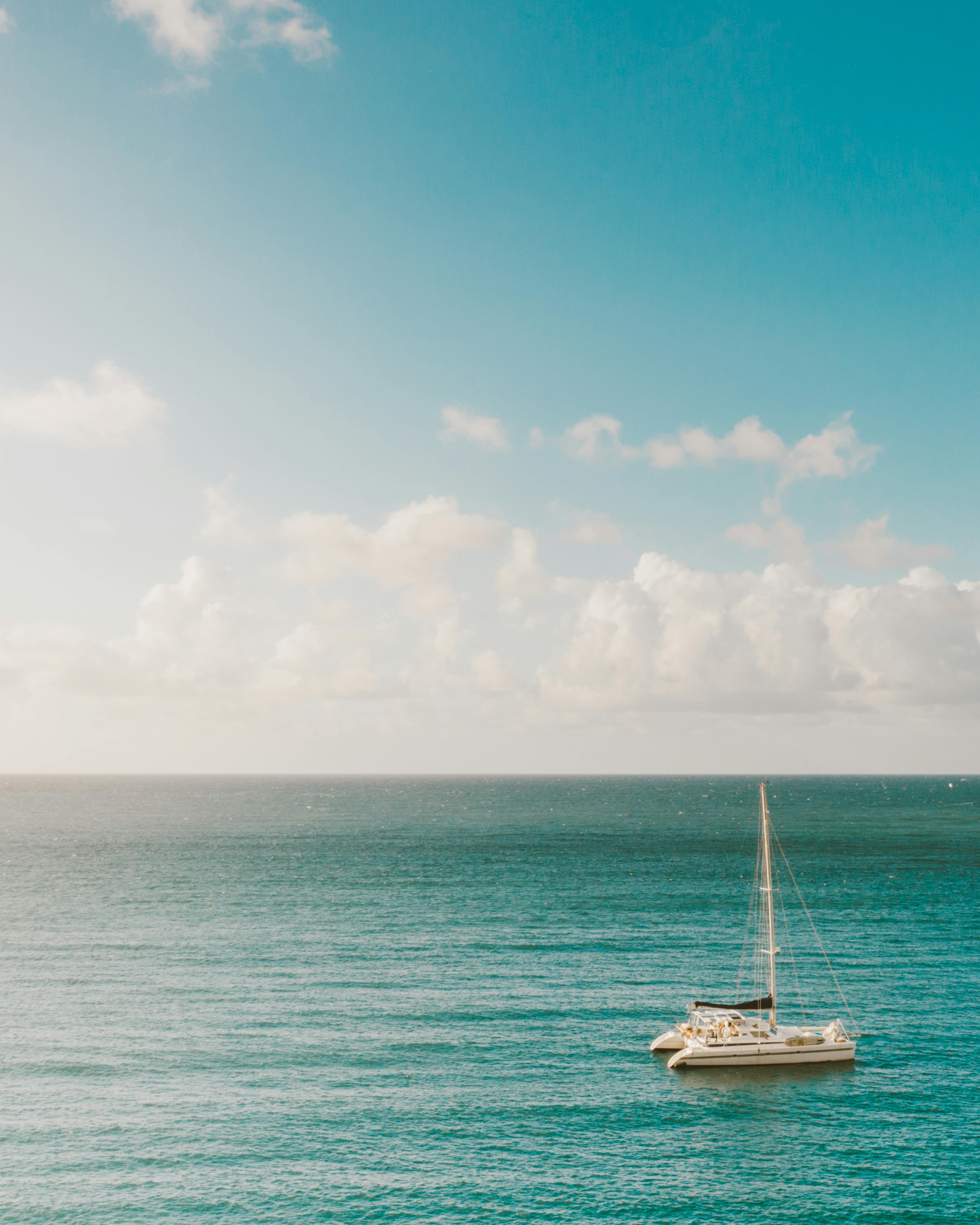 一艘孤独的帆船漂浮在蔚蓝的天空下宁静的海面上