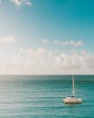 一艘孤独的帆船漂浮在蔚蓝的天空下宁静的海面上
