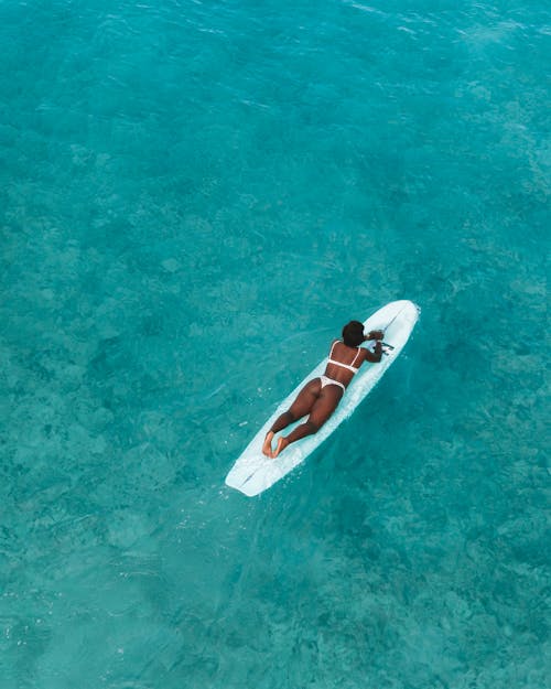 Woman Lying on Surfboard on Sea