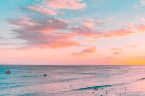 Free A breathtaking seascape with a pink sky at sunset, featuring calm waters and boats offshore. Stock Photo