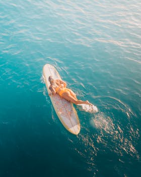 一名女子在冲浪板上穿过宁静的海浪，放松身心