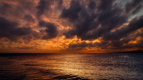 Free A breathtaking sunset over the ocean with dramatic clouds creating a stunning view. Stock Photo