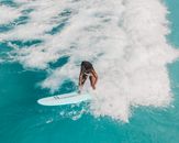 女子在碧绿的海浪上冲浪，展现了水上运动的技巧与刺激