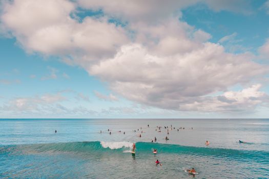 冲浪者在碧绿的海浪上，享受着风景如画的天空下阳光明媚的一天