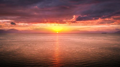 Free Dramatic sunset over the ocean with vivid colors and serene waters, creating a peaceful seascape. Stock Photo