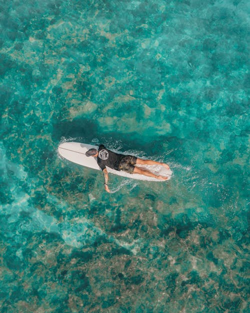 High Angle View of Turquoise Water and Man Lying Down on Surfboard 