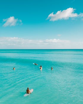 Surfers enjoying the turquoise sea on a bright summer day, perfect for adventure and fun.