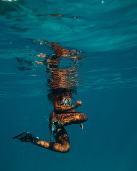 夏日的大海中，一名女子正在水下游泳，展现出大海的美丽