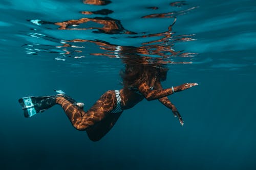 Woman in Striped Bikini and Flippers Swimming in Water