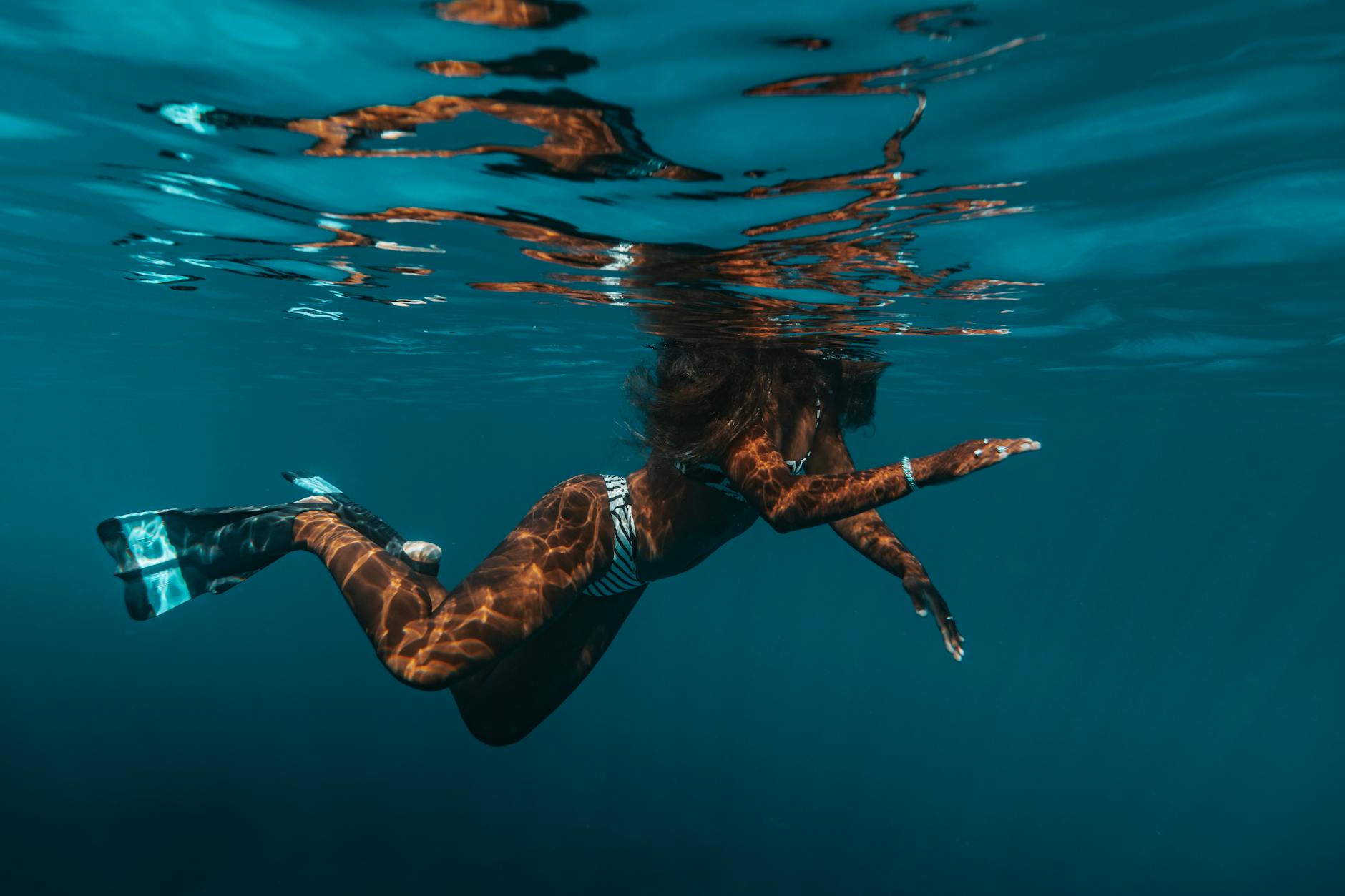 Woman in Striped Bikini and Flippers Swimming in Water