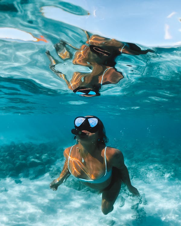 Een meisje in haar bikini met een duikbril op die aan het snorkelen is
