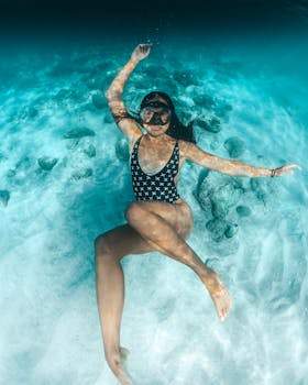 一位身着时尚黑色泳衣、戴着潜水面具的女子优雅地漂浮在水下