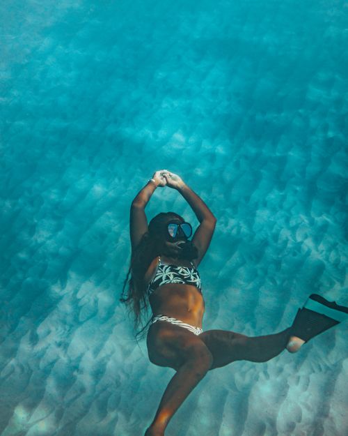 Free A woman in a bikini and dive mask gracefully swimming underwater. Stock Photo