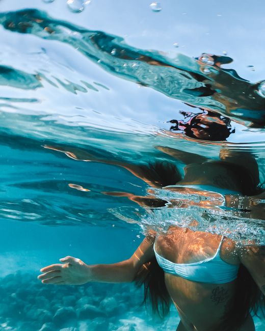 Artistic underwater photo of a woman in swimwear captured in a vibrant ocean setting.