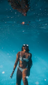 一位时尚女子穿着比基尼、戴着潜水面具在水下游泳