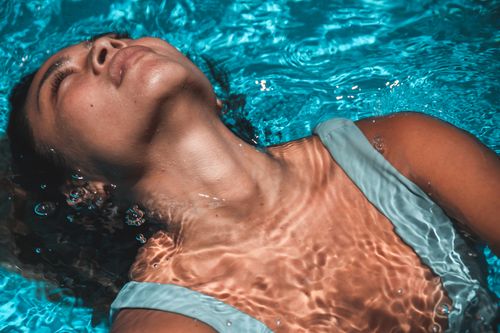 Free Close-up of a woman with eyes closed, floating peacefully in a swimming pool. Stock Photo