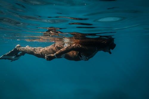 Free Person in White and Blue Striped Swimsuit Swimming in the Blue Water  Stock Photo