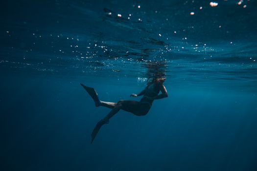 一个女人优雅地潜入深蓝色的海洋，营造出宁静而充满冒险感的场景
