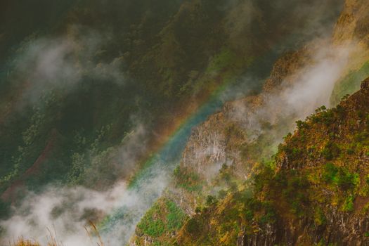 一道充满活力的彩虹横跨迷雾笼罩的山地，营造出宁静而风景如画的景色