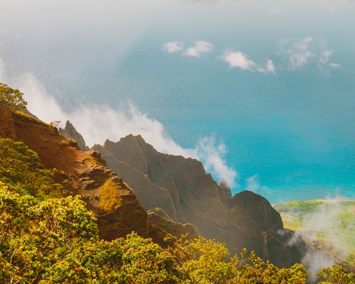 Free Stunning aerial perspective of rugged coastal mountains overlooking the ocean on a bright day. Stock Photo