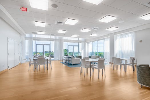 A well-lit, spacious common room with modern interior design, tables, and seating.