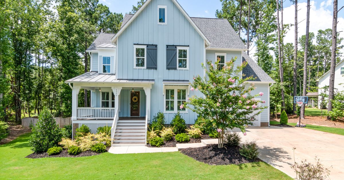 Charming blue cottage with shutters and a lush garden, exuding tranquility and elegance.