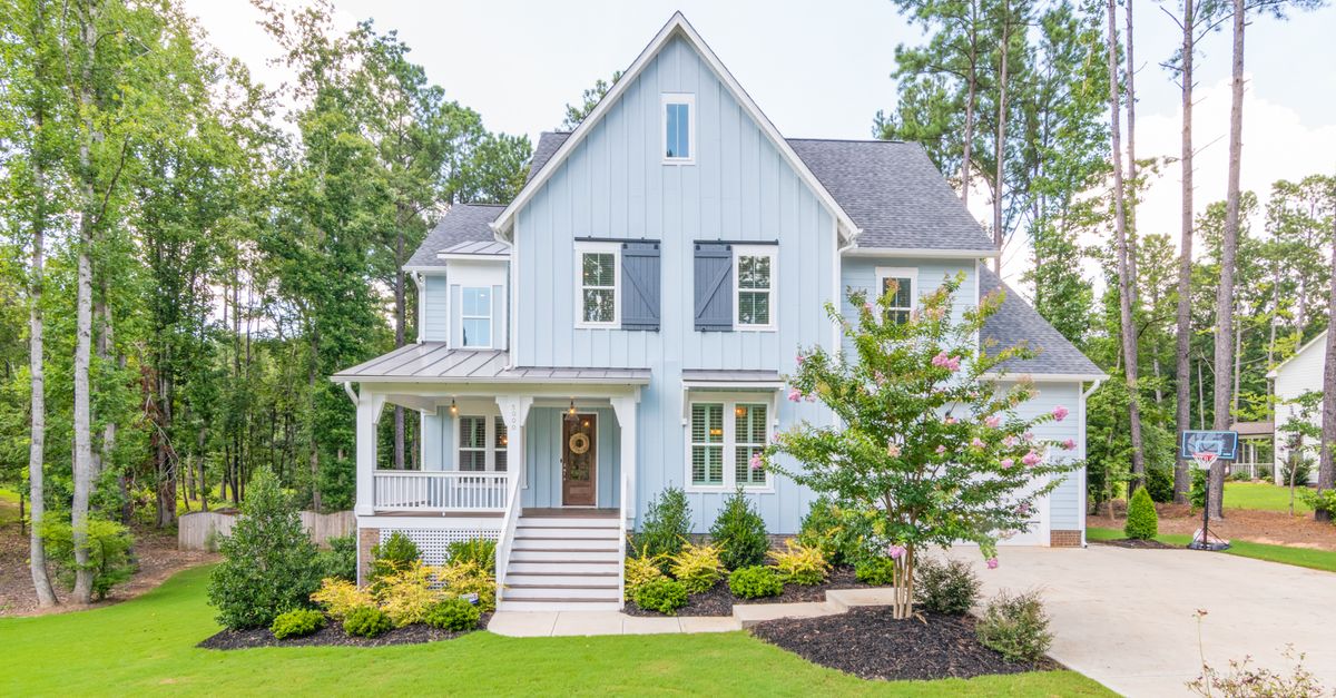 A beautiful suburban home surrounded by trees and a well-maintained lawn.