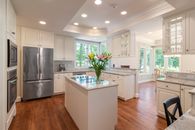 Silver French Door Refrigerator Beside White Wooden Kitchen Cabinet