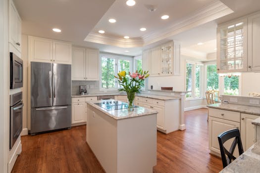 Bright and open modern kitchen featuring white cabinetry, stainless steel appliances, and a flower bouquet.