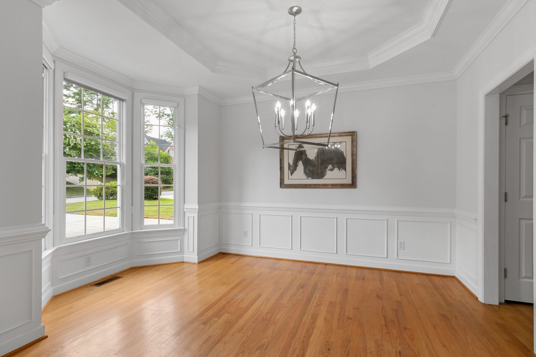 Empty modern interior room with large windows, wooden floor, and elegant lighting.
